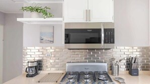 Cucina con piano cottura a gas, forno a microonde e pensili bianchi.