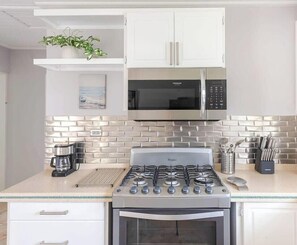 A kitchen with a gas stove, microwave, and white cabinets.