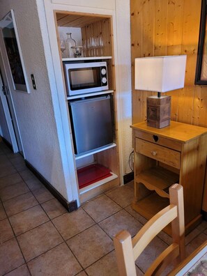 Compact kitchen area with microwave and oven, wooden cabinet, and wine storage.