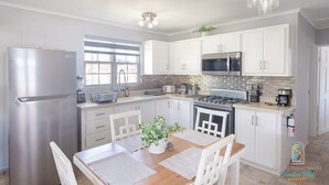 Eine moderne Küche mit weißen Schränken, Edelstahlgeräten und einem Essbereich mit einem Holztisch und Stühlen.