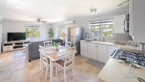 Eine moderne Küche mit Essbereich, eingebauten Geräten und großen Fenstern.