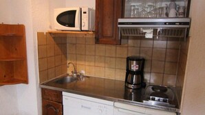 A compact kitchen with a microwave, coffee maker, and a sink.