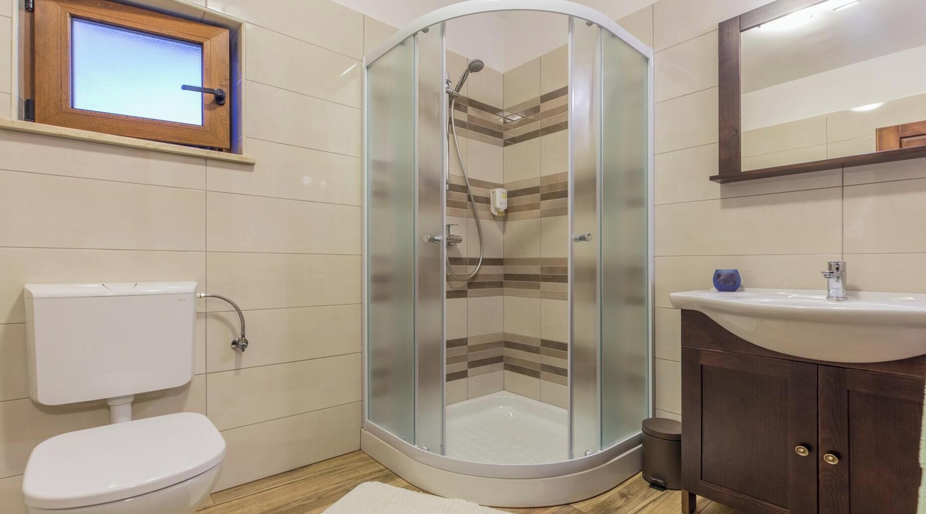 Une salle de bain avec une douche à parois de verre, des toilettes, un lavabo et un meuble en bois.