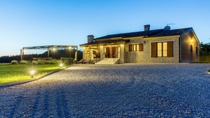 A stone house with a gravel driveway and a covered outdoor seating area. - Modern Villa Elida with pool (Heki)