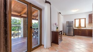 A kitchen with a wooden ceiling, a sliding glass door leading to an outdoor area, and a refrigerator. - Modern Villa Elida with pool (Heki)