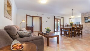A living room with a sofa, coffee table, and a dining area with chairs and a table. - Modern Villa Elida with pool (Heki)