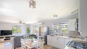 Een ruime keuken met een eethoek, een televisie en een plafondventilator.