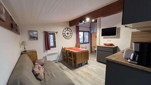A compact living space with a sofa, a dining table, a kitchen area with a coffee machine, and a TV mounted on the wall. - 20m from ski slopes, 6th floor, tv, ski locker, 27m², Alpe d'Huez (L'Alpe d'Huez)