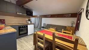 A compact kitchen with modern appliances, a dining area with wooden furniture, and a cozy living space with a sofa and a small table. - 20m from ski slopes, 6th floor, tv, ski locker, 27m², Alpe d'Huez (L'Alpe d'Huez)