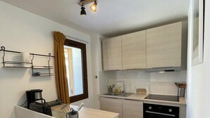 Uma cozinha compacta com uma ilha central, forno embutido e pia.