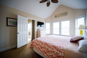 Un dormitorio con cama, ventilador de techo, un cartel que dice 'Guest Cottage' y ventana con persianas.