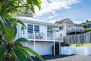 Une maison à deux étages avec un balcon, un garage et une clôture en bois.