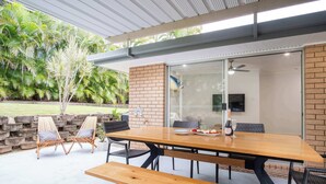 An outdoor patio with a wooden table, chairs, and a bench.