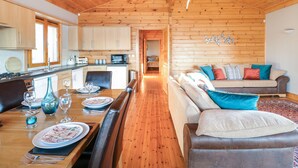 A cozy cabin interior with a wooden dining area, a sofa, and a kitchen with wooden cabinets. - Osprey Lodge (Lincoln)