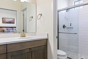A bathroom with a white sink, a mirror, a shower with a glass door, and a toilet. - Rally Point BRAND NEW, PICKLEBALL, KID-FRIENDLY! (Washington)