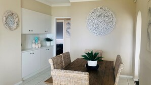A dining area with a wooden table, wicker chairs, and a potted plant. - Sunset on Loralyn by Book Jervis Bay (Saint Georges Basin)
