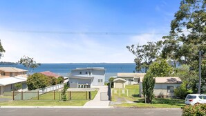 A coastal residential area with houses, a clear sky, and a view of the sea. - Sunset on Loralyn by Book Jervis Bay (Saint Georges Basin)