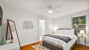 Ein Schlafzimmer mit einem Bett, einer Stehlampe, einem Deckenventilator und einem Fenster mit Jalousien.