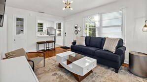 Ein Wohnzimmer mit einer Couch, einem Couchtisch und einer Küche im Hintergrund.