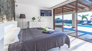 Een moderne slaapkamer met een bed, nachtkastje en een televisie.