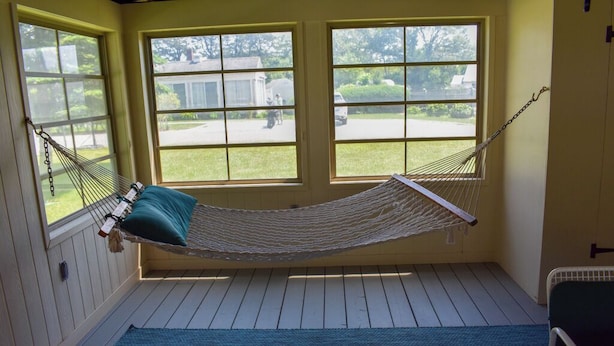 A hammock in a room with wooden floors and large windows. - 3 bedroom home with ac, walk to the beach! (West Dennis)