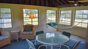A cozy room with wicker furniture, a glass table, and a hammock. - 3 bedroom home with ac, walk to the beach! (West Dennis)