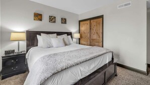 A bedroom with a bed, bedside tables, a wardrobe, and wall art. - Modern 2BR Condo - Near Ski Lift; Walk Everywhere! (Park City)