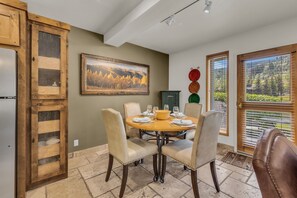 A dining area with a round table, chairs, and a painting on the wall.