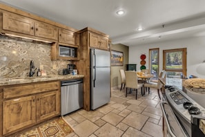 A modern kitchen with wooden cabinets, stainless steel appliances, and a dining area with a view.
