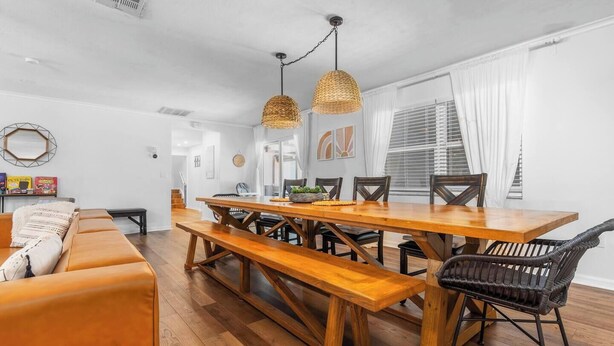 A dining area with a wooden table and benches, surrounded by wicker chairs. - Massive Beach House, 6BR 8BA, Heated Pool, Pickleball, Hot tub, Gym, Sleeps 22 (Bradenton)