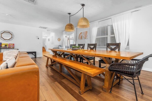 A dining area with a wooden table and benches, surrounded by wicker chairs. - Massive Beach House, 6BR 8BA, Heated Pool, Pickleball, Hot tub, Gym, Sleeps 22 (Bradenton)