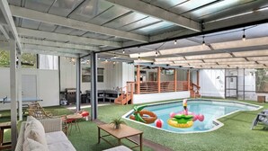 A covered outdoor area with a pool, artificial grass, and outdoor furniture. - Massive Beach House, 6BR 8BA, Heated Pool, Pickleball, Hot tub, Gym, Sleeps 22 (Bradenton)