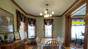 A dining room with a wooden table, six chairs, a chandelier, and a large rug. - Gateway to the North Shore! Spacious home 2.5 blocks from Lake Superior! (Two Harbors)