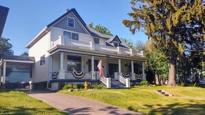 A two-story house with a front porch, a garage, and a well-maintained lawn. - Gateway to the North Shore! Spacious home 2.5 blocks from Lake Superior! (Two Harbors)