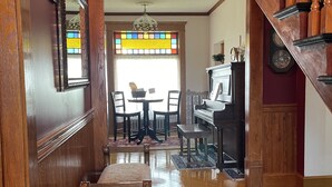 A wooden hallway with a staircase, a dining area with a table and chairs, and a piano. - Gateway to the North Shore! Spacious home 2.5 blocks from Lake Superior! (Two Harbors)