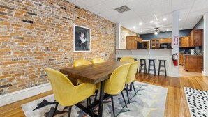 Un coin repas avec un mur en briques, une table en bois et des chaises jaunes.