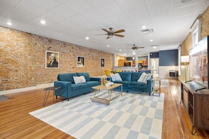 Ein geräumiger Wohnbereich mit zwei blauen Sofas, einem Holztisch und einem karierten Teppich.