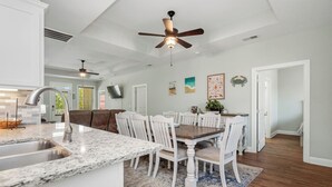 A kitchen with a granite countertop, white cabinetry, and a ceiling fan. - Pawsitively Paradise: Dog-friendly Home with Fenced Yard Close to Beach, Shops a (Oak Island)