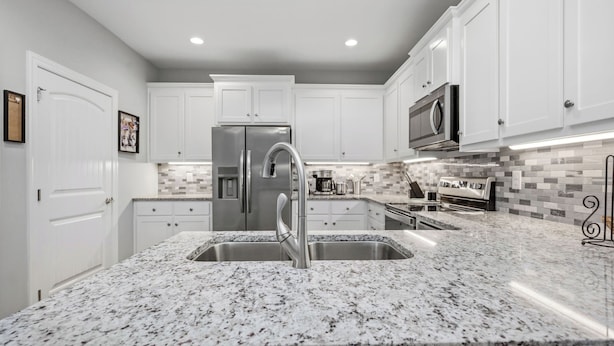 A modern kitchen with white cabinets, a stainless steel refrigerator, a double sink, and a microwave. - Pawsitively Paradise: Dog-friendly Home with Fenced Yard Close to Beach, Shops a (Oak Island)