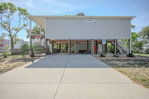 A single-story building with a covered porch, a garage, and a small outdoor seating area.