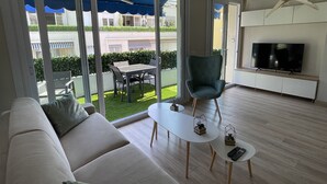 En moderne stue med sofa, spisebord og fjernsyn.