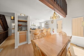 A spacious kitchen with white cabinets, a wooden dining table, and a staircase with wooden railings. - Mountain Shadows Chalet Tahoe Fun Awaits (Incline Village)