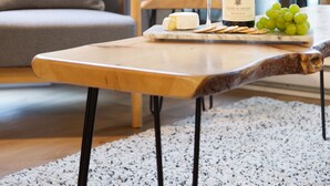 Un salon moderne avec une table basse en bois, une bouteille de vin, un verre et un bol de raisins.