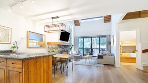 Un vaste espace de vie comprenant un salon avec cheminée, un coin repas et une cuisine dotée de meubles en bois.