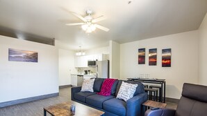 A modern living room with a sofa, coffee table, and a dining area with a table and chairs.