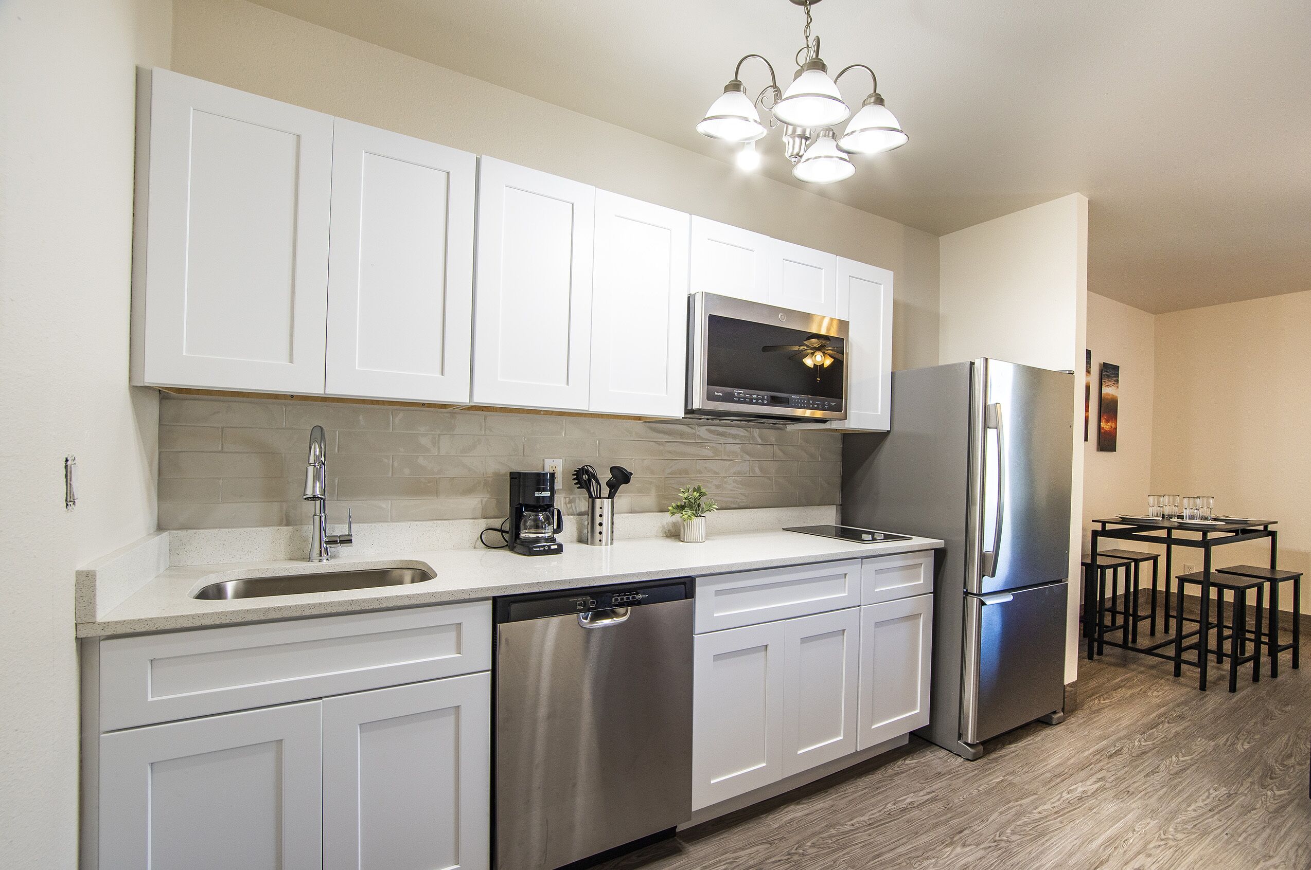 A modern kitchen with white cabinets, stainless steel appliances, a dishwasher, and a coffee maker.