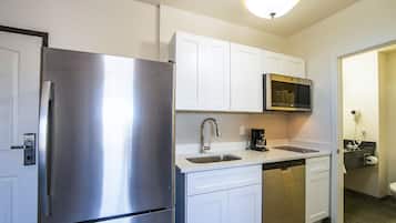 Una cocina moderna con electrodomésticos de acero inoxidable, armarios blancos y un microondas integrado.