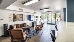 A modern hotel lobby with a sofa, chairs, a small table, and a trash can.