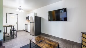 A compact kitchen with a refrigerator, microwave, and a dining area with a table and chairs.