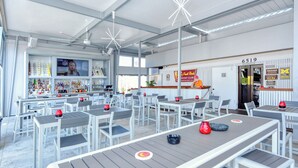 Ein geräumiger Innenbereich mit mehreren Tischen und Stühlen, eine Bar mit Fernseher, der die NFL zeigt, und ein Schild mit der Adresse 6519.